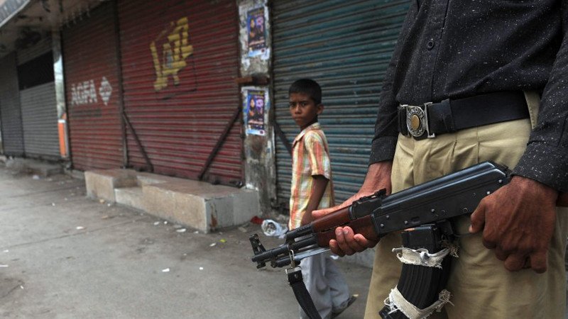A Pakistani boy walks past a policeman on duty in a troubled area of Karachi on August 13, 2011. The independent Human Rights Commission of Pakistan says 800 people, most of them poor, have died since January, including 300 last month alone. AFP PHOTO/Rizwan TABASSUM