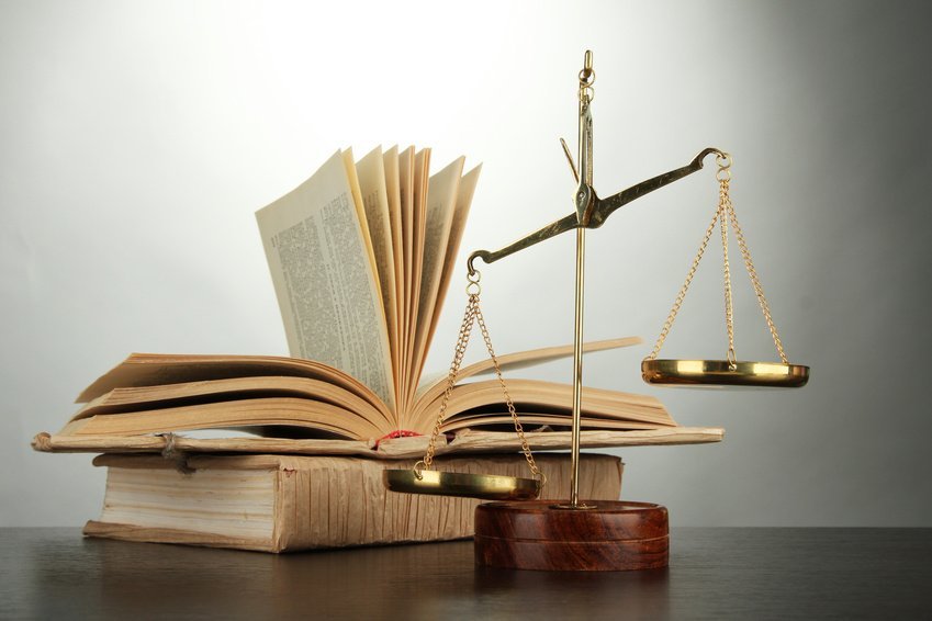 Gold scales of justice and books on grey background