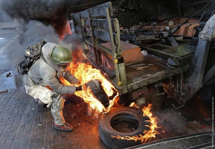 A protester pulls a burning tyre during clashes with police in Kiev