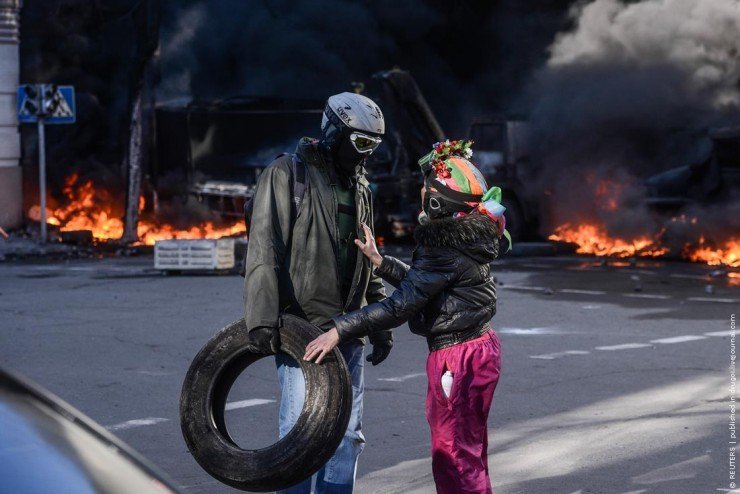 People speak near a barricade on fire during clashes between anti-government protesters and Interior Ministry members in Kiev