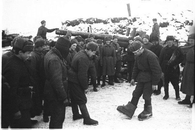 На фото: Советский солдат под Сталинградом показывает немецкие "караульные боты".
